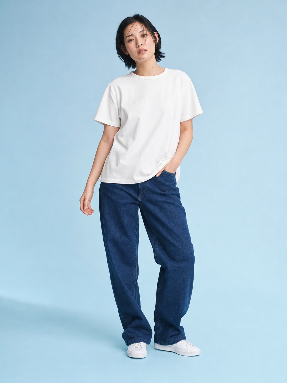 East Asian woman wearing the white T-shirt in a blue studio